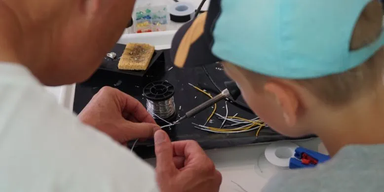 Gemeinsam tüfteln ein Freiwilliger und ein Junge