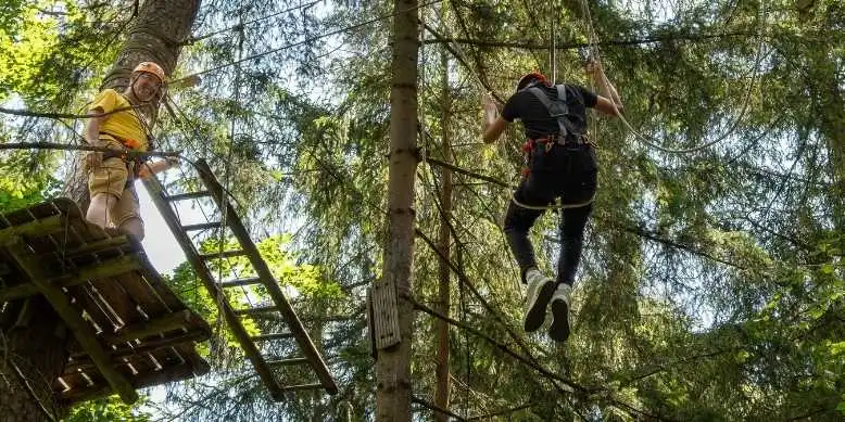 Mit dem Patenkind im Kletterwald - zwei Personen hängen im Parcous