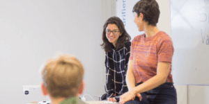 Frau steht an einem Whiteboard und erklärt